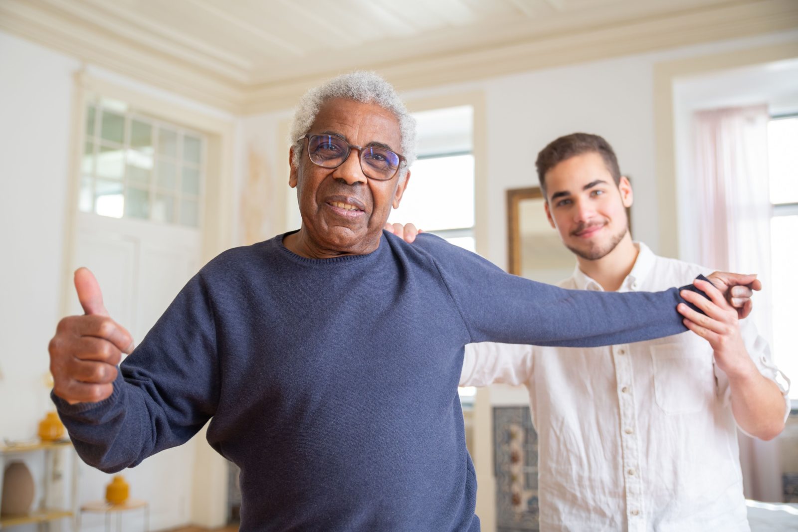 A caregiver supporting a smiling older man at home