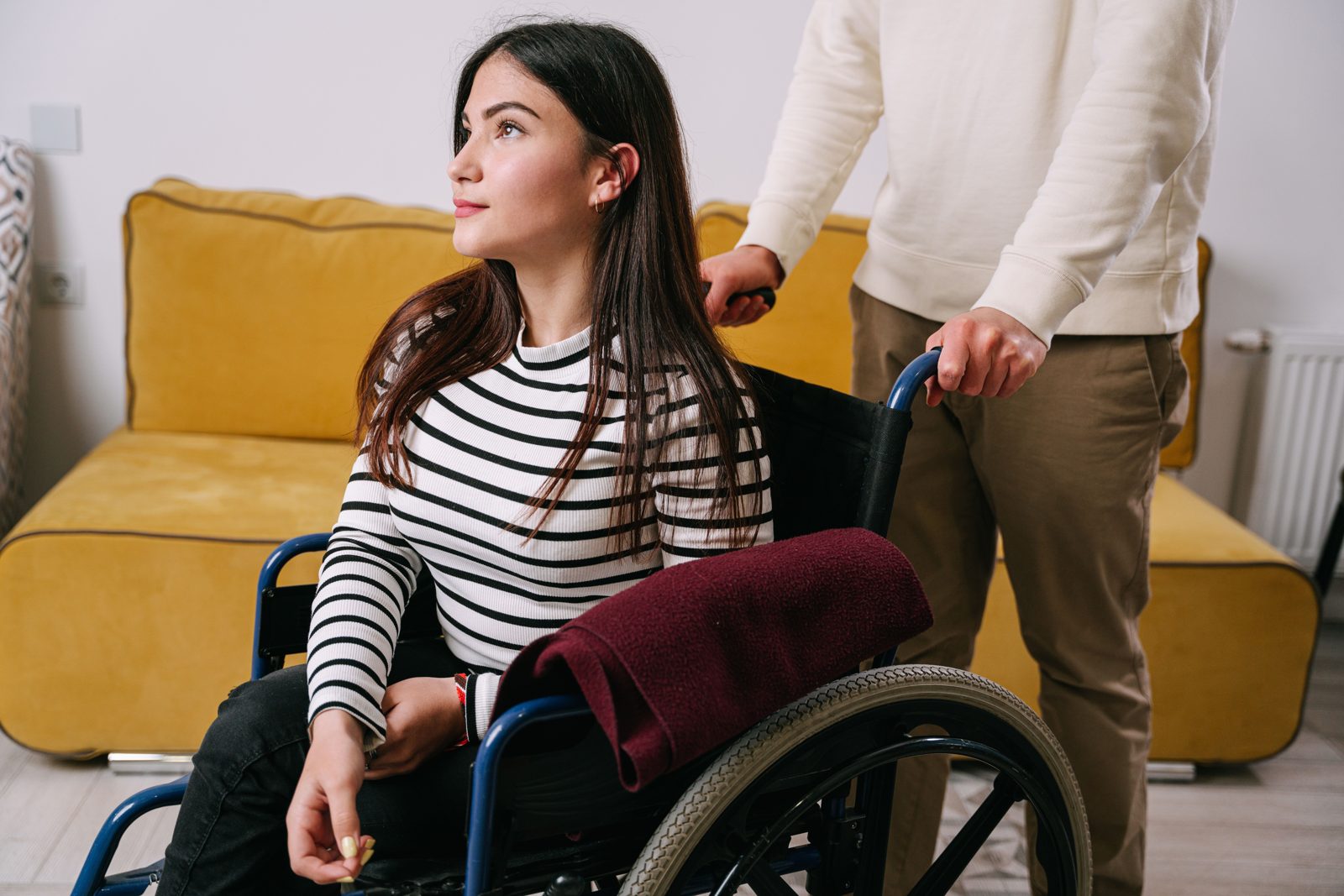 A caregiver helping a young woman in a wheelchair at home