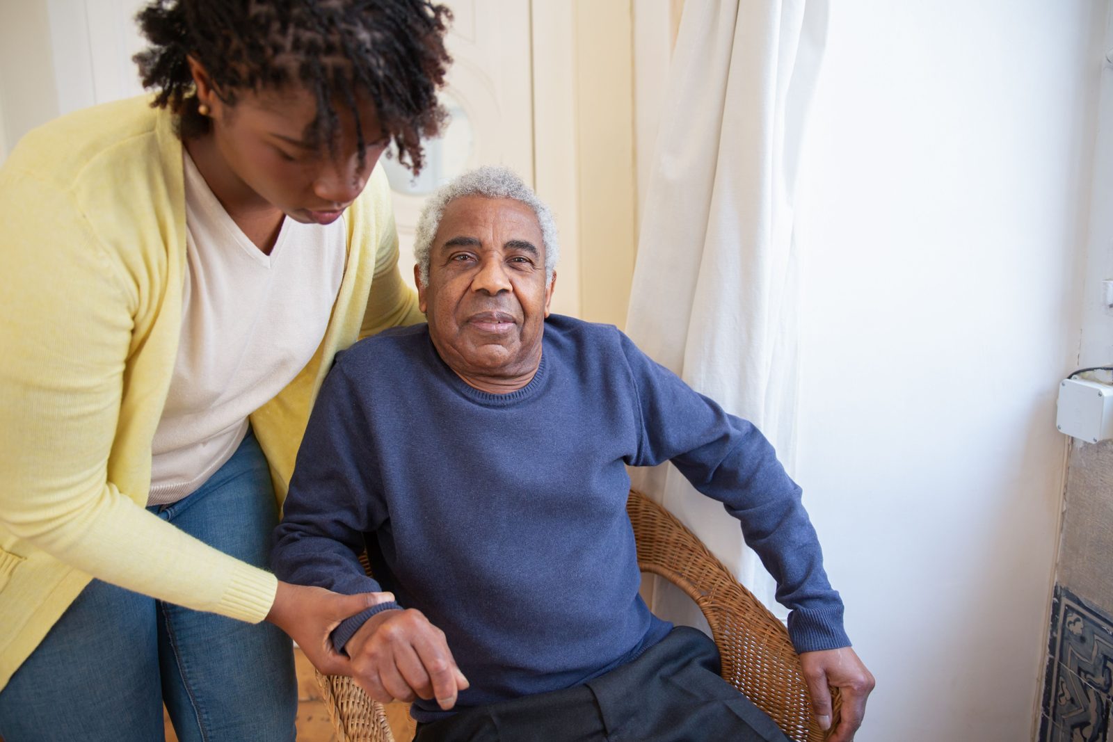 A caregiver gently assisting an older man seated at home